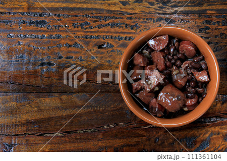 pot with feijoada, traditional brazilian cuisine dish, isolated under wooden background 111361104