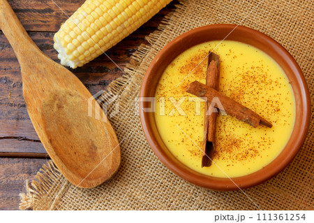 Curau, cream of corn sweet and dessert typical of the Brazilian cuisine, with cinnamon placed in ceramic bowl on wooden table. Top view Curau, cream of corn sweet and dessert typical of the Brazilian cuisine, with cinnamon placed in ceramic bowl on wooden table. Top view 111361254