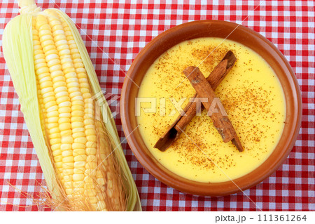 curau, cream of sweet corn and dessert typical of the Brazilian cuisine, with cinnamon placed in a ceramic bowl on a checkered tablecloth. 111361264
