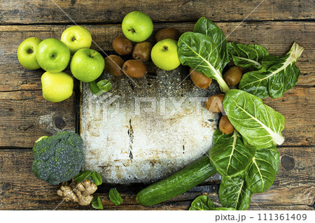 Fruits and vegetables with old empty tray on a rustic wooden table. Green, detox, healthy diet concept. Apples, broccoli, kiwi, spinach and cucumber. Copy space, add text. Top view, flat lay 111361409