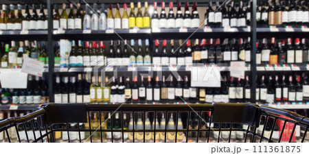 Abstract blurred image of alcohol store with trolley in department store. (Selective focused at shopping cart) Abstract blurred image of alcohol store with trolley in department store. (Selective focused at shopping cart) 111361875