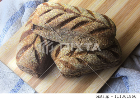 Australian bread on spatula, leaving oven, on rustic wooden background. Traditionally this bread is made with chocolate powder, brown sugar and honey Australian bread on spatula, leaving oven, on rustic wooden background. Traditionally this bread is made with chocolate powder, brown sugar and honey 111361966