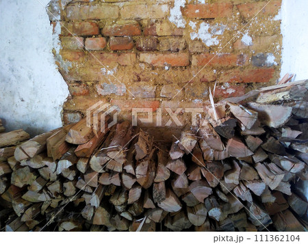 Firewood stack for winter to feed fireplace, with rustic wall background. 111362104