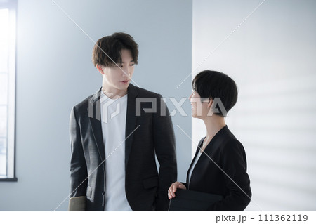 パソコンを持ちジャケットやスーツを着た男女の会話 111362119