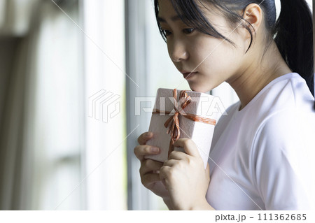 ギフトボックスを持ち悩む女子高校生 111362685