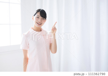 白衣やナース服を着た笑顔の女性の看護師、ナース、ヘルパーの指差しおすすめ上半身 白衣やナース服を着た笑顔の女性の看護師、ナース、ヘルパーの指差しおすすめ上半身 111362790