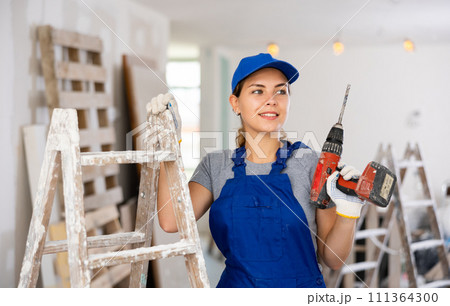 Portrait of young woman builder with drill 111364300