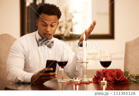 Confused, angry and phone fail of a date of a black man waiting at a restaurant table. Internet 5g video call of a guy using smartphone to ask a why question and check late time on Valentines Day 111365126