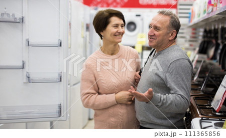 Middle aged wife and husband picking new refrigerator in store Middle aged wife and husband picking new refrigerator in store 111365856