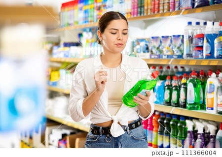 Interested young woman choosing household chemicals in store 111366004