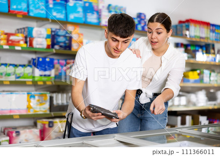 in supermarket couple choose nosh near showcase-refrigerator 111366011