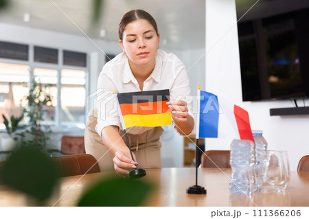 Young woman puts flags of Germany and France on table 111366206
