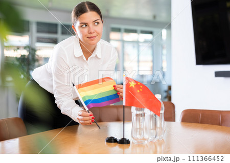 Young lady sets miniatures flags of Chinа and LGBT before international negotiations Young lady sets miniatures flags of Chinа and LGBT before international negotiations 111366452