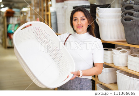 Woman choosing plastic storage basket at store Woman choosing plastic storage basket at store 111366668