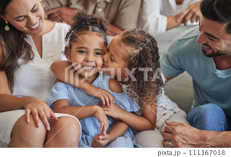Sibling love, family and kiss with children sharing a special sister bond while at home with mom and dad for bonding and to relax. Happy latino girl kids or friends sitting with man and dad parents 111367018