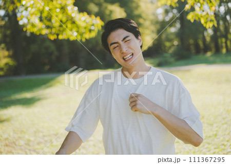 暑くて服をパタパタする男性 111367295