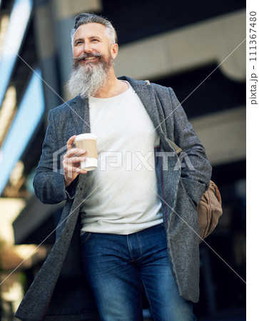 confident mature businessman man walking in city street holding coffee enjoying urban lifestyle 111367480
