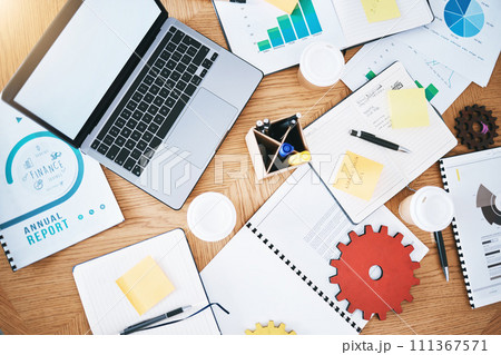 Documents, finance and report with a laptop, gear and paperwork on a table or desk in a corporate office from above. Notepad, stationery and graphs on a wooden surface in a workplace for planning Documents, finance and report with a laptop, gear and paperwork on a table or desk in a corporate office from above. Notepad, stationery and graphs on a wooden surface in a workplace for planning 111367571