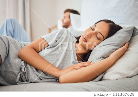 Sleeping, peace and woman asleep on bed with comfortable pillow while taking nap to relax with sleepless partner in background. Couple, sexual problems and carefree wife lying eyes closed next to man Sleeping, peace and woman asleep on bed with comfortable pillow while taking nap to relax with sleepless partner in background. Couple, sexual problems and carefree wife lying eyes closed next to man 111367629
