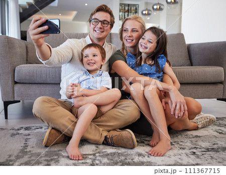 Selfie, phone and family with a man taking a picture with his children and their mother on the floor of their living room at home. Happy, love and kids with a brother and sister posing with parents Selfie, phone and family with a man taking a picture with his children and their mother on the floor of their living room at home. Happy, love and kids with a brother and sister posing with parents 111367715