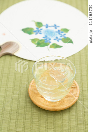 畳に置かれた冷茶とうちわ 111368759