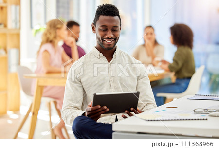 African businessman working on a digital tablet while sitting by his desk in a corporate office. Happy, professional and black man doing research on the internet or a website with a mobile device. 111368966