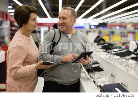 Senior couple choosing tablet in tech store Senior couple choosing tablet in tech store 111369219