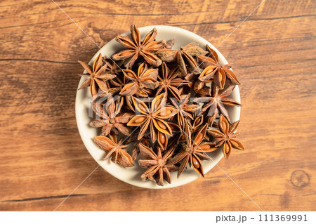 anise stars in a white bowl on wooden table 111369991