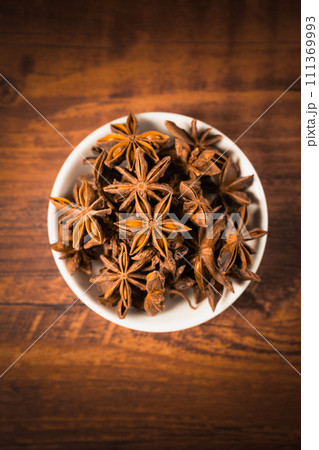 anise stars in a white bowl on wooden table 111369993