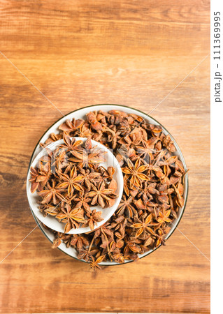 anise stars in a white bowl on wooden table 111369995