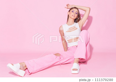 Young fashion woman in pink trendy jeans and white top on pink background. 111370280