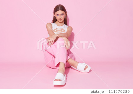 Young fashion woman in pink trendy jeans and white top on pink background. Young fashion woman in pink trendy jeans and white top on pink background. 111370289