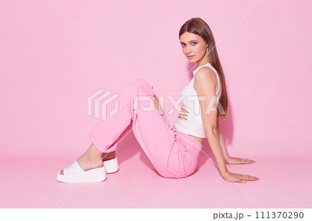 Young fashion woman in pink trendy jeans and white top on pink background. Young fashion woman in pink trendy jeans and white top on pink background. 111370290