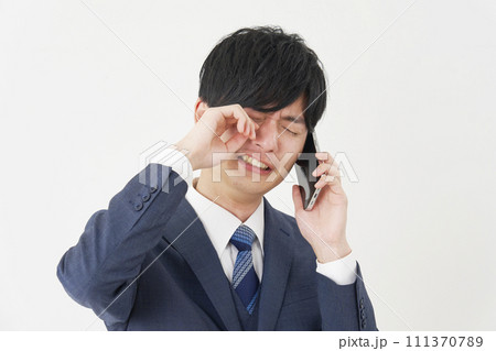 泣きながらスマートフォンで電話するビジネスマン　白背景 111370789