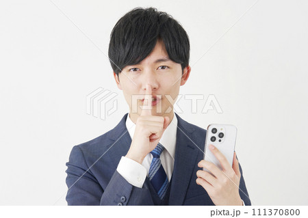 スマートフォンを持って秘密のポーズをするビジネスマン　白背景 111370800