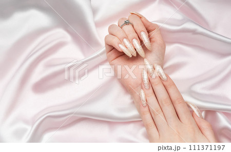 Female Hands on a white silk background with beautiful pearl manicure.Hands on a brown background and beautiful pearl manicure Female Hands on a white silk background with beautiful pearl manicure.Hands on a brown background and beautiful pearl manicure 111371197
