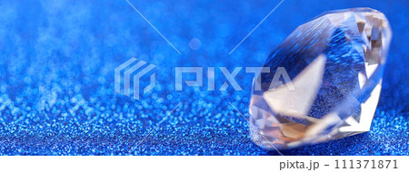 Grand royal pure diamond on blue sparkling sequins background, macro . Big brilliant closeup. 111371871