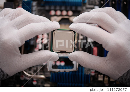 Unrecognizable technician carefully holding CPU with fingers before inserting it into PC mainboard 111372077