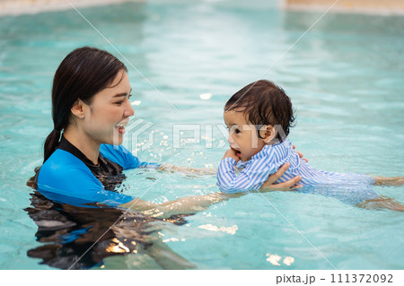 mother teaching her daughter swimming in pool 111372092