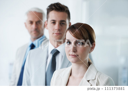 Portrait of three corporate business people , standing in a row and in broad room. Smiling friendly group of three business partners of different age private company staff posing for office Portrait of three corporate business people , standing in a row and in broad room. Smiling friendly group of three business partners of different age private company staff posing for office 111373881