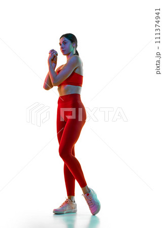 Hand stretching and warming up exercises. Young woman training against white studio background in neon light Hand stretching and warming up exercises. Young woman training against white studio background in neon light 111374941