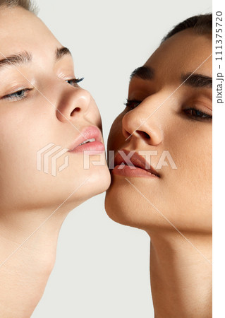 Close-up portrait of beautiful tender girls with different skin tones posing against white studio background. Foundation 111375720