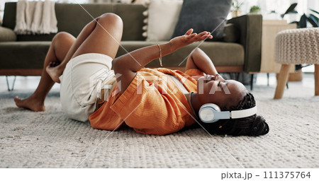 Music, headphones and black woman on floor, listening to song and audio in living room. Happy African person on radio, streaming sound and technology for freedom, relax on carpet and smile in home 111375764