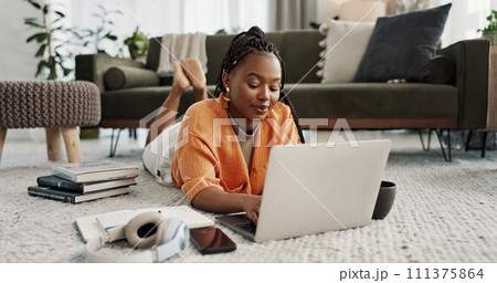 Laptop, education and a student black woman on the floor of a living room to study for a test or exam. Computer, smile and a happy young person learning with an online course for upskill development 111375864