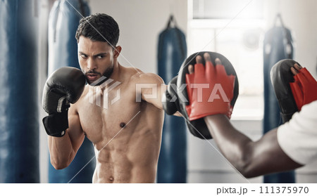 Boxing pad, sports man and gym exercise coaching with personal trainer expert for tournament. Strong, muscular and tough mma athlete doing fitness practice for wellbeing and punch discipline. Boxing pad, sports man and gym exercise coaching with personal trainer expert for tournament. Strong, muscular and tough mma athlete doing fitness practice for wellbeing and punch discipline. 111375970