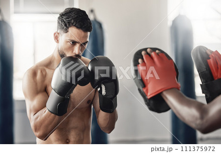 Boxing gym, fighting pad and man training with athlete coach for a fitness cardio exercise session. Strength, focus and fighter workout for punch technique with professional sports equipment. Boxing gym, fighting pad and man training with athlete coach for a fitness cardio exercise session. Strength, focus and fighter workout for punch technique with professional sports equipment. 111375972
