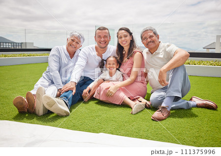 Portrait of happy big family with girl, love and a smile while sitting on backyard, lawn or grass. Grandfather, grandmother and mom with dad and child or kid bonding outside home in the sunshine. Portrait of happy big family with girl, love and a smile while sitting on backyard, lawn or grass. Grandfather, grandmother and mom with dad and child or kid bonding outside home in the sunshine. 111375996