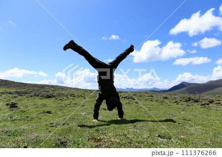 Woman hiker doing a handstand on high altitude mountain meadow 111376266