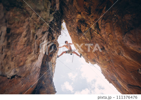 Mountain or rock climbing, cliff hanging and adrenaline junkie with courage on adventure trying to balance between gap. Athletic climber man doing fitness, exercise and workout during extreme sport 111376476