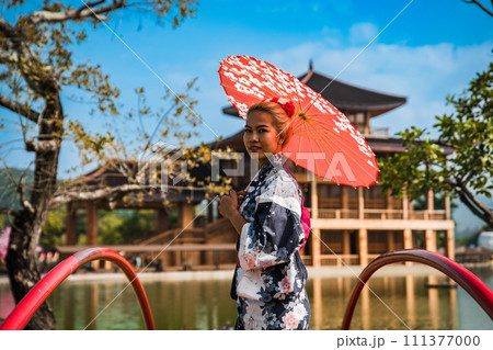 Asian girl in kimono and umbrella in Japanese theme park Hinoki Land in Chai Prakan District, Chiang 111377000